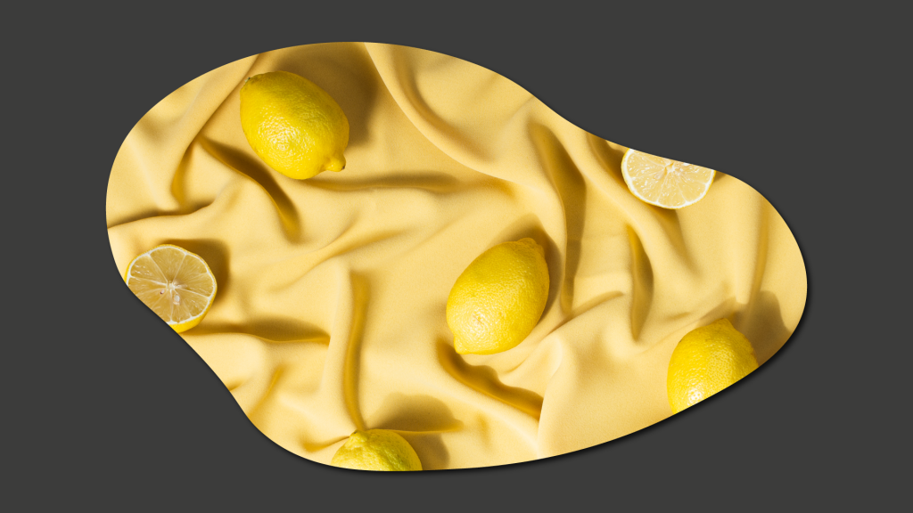 Fotografía artística de unos limones enteros y partidos sobre una tela amarilla. La finalidad es informar sobre el servicio de fotografía y vídeo profesional que ofrece PINK LEMON
